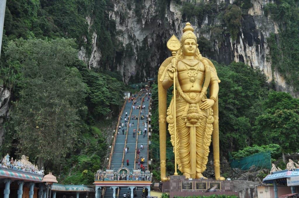 Golden statue in front of long entry stairs to Batuh Caves